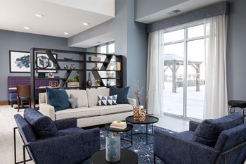 A living room with a white sofa, a blue chair, and a glass table.