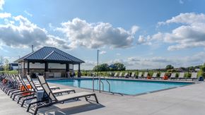Maple Grove apartment for rent - A pool with sun loungers and a pavilion is surrounded by a fence. at The Edison at Maple Grove, Minnesota, 55311