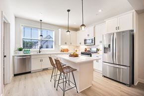 Blaine townhouse for rent - a white kitchen with stainless steel appliances and a white island with two stools at Foxtail Hollow Townhomes, Minnesota
