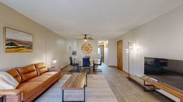 Fridley apartment for rent - A living room with a brown leather couch and a painting of a landscape on the wall.
