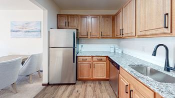 A kitchen with wooden cabinets and a stainless steel refrigerator.