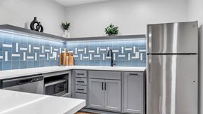 Roseville apartment for rent - A modern kitchen with a stainless steel refrigerator and a backsplash of blue tiles. at Hillsborough Apartments, Minnesota