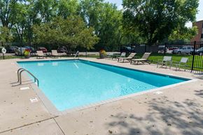 New Brighton apartment for rent - a swimming pool with lounge chairs and trees in the background