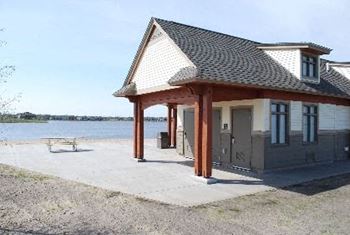 A small house with a patio next to the water