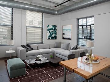 Minneapolis apartment for rent - A modern living room with a grey sofa, a green ottoman, a wooden coffee table, and a painting on the wall.