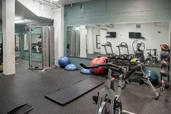 A gym with a variety of equipment including a stationary bike, a rowing machine, and a bench.