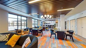 Minneapolis apartment for rent - A modern office space with a variety of seating options and a colorful carpet at The Bessemer at Seward Commons Apartments, Minneapolis, MN,  55404
