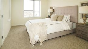 Minneapolis apartment for rent - A bedroom with a large bed and a lamp on the side table at The Bessemer at Seward Commons Apartments, Minneapolis, Minnesota