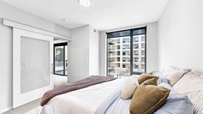 Minneapolis apartment for rent - A bedroom with a large bed and a view of a cityscape through the window.