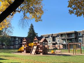 Brooklyn Park apartment for rent - a playground in front of an apartment complex with a tree