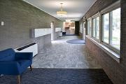 St Anthony apartment for rent - a hallway with a blue chair on the left and a brick wall on the right