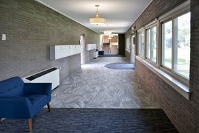St Anthony apartment for rent - a hallway with a blue chair on the left and a brick wall on the right