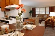 Brooklyn Park apartment for rent - a living room with a wooden table and a kitchen in the background at Point of America Apartments,Brooklyn Park, Minnesota