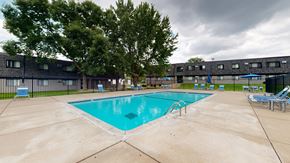 Anoka apartment for rent - a swimming pool with chaise lounge chairs and umbrellas in front of a building