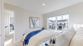 East Bethel townhouse for rent - A bedroom with a large bed and a window overlooking a building.
