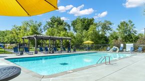 Shoreview apartment for rent - A sunny day at the pool with a yellow umbrella providing shade.