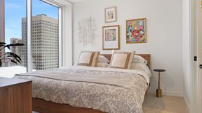 St. Paul apartment for rent - A bedroom with a large bed and a city view through the window.