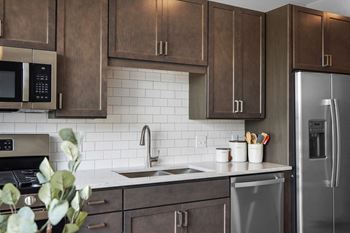 A kitchen with dark wood cabinets and white countertops