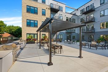 An outdoor patio with a grill and tables and chairs