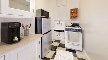A kitchen with white cabinets and a checkered floor