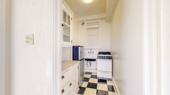 A small kitchen with white cabinets and a black and white checkered floor