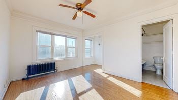 A bedroom with a ceiling fan and three windows
