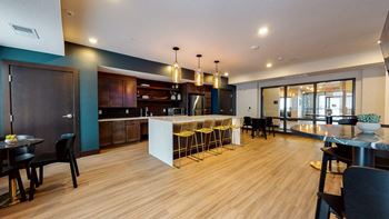 A kitchen and dining area with a large white island and yellow bar stools