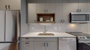 Minneapolis apartment for rent - A modern kitchen with a stainless steel refrigerator, a white sink, and a microwave above the stove.at Tyler Street Stacks, Minneapolis, MN 55413