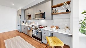 Minneapolis apartment for rent - A modern kitchen with a yellow chair and white cabinets.