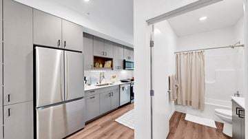 Minneapolis apartment for rent - A modern kitchen with a refrigerator, cabinets, and a bathroom with a shower.