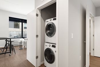 A white washing machine is built into a wall in a modern laundry room.