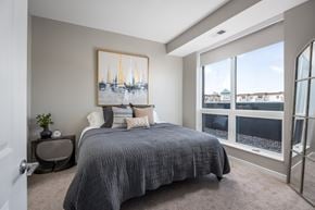 Waconia apartment for rent - A bedroom with a large bed and a painting of sailboats on the wall.