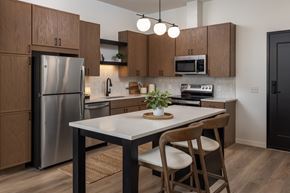 Rosemount apartment for rent - A kitchen with a table and chairs in the foreground and a refrigerator, microwave, and oven in the background.