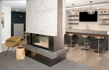 Cozy clubroom with indoor fireplace, coffee bar, and workspace.