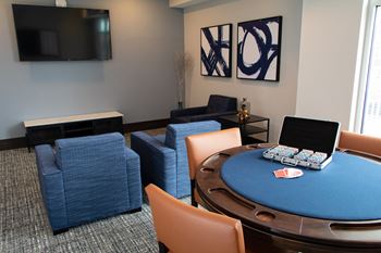 A poker table with chairs and a laptop on it.