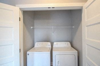 Two white washing machines in a small laundry room.