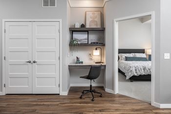 A room with a desk, chair, and bed.