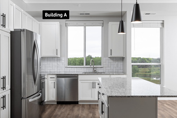 A modern kitchen with white cabinets and a black refrigerator.