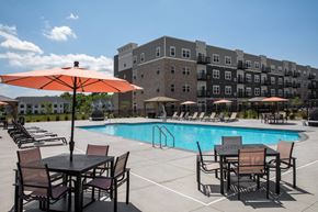 Woodbury apartment for rent - A pool area with chairs and umbrellas in front of a building at The Edison at Woodbury, Woodbury, 55129