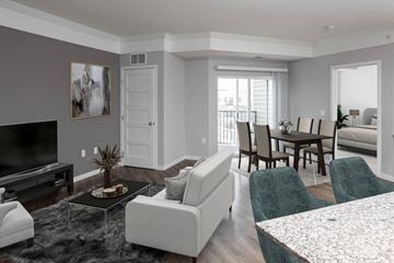 Woodbury apartment for rent - A living room with a grey couch, a black television, and a coffee table with a vase of flowers on it.