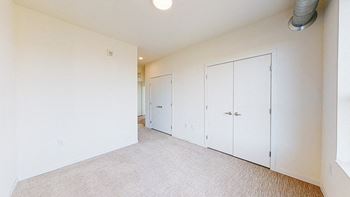 A room with white walls and a carpeted floor with three white doors.