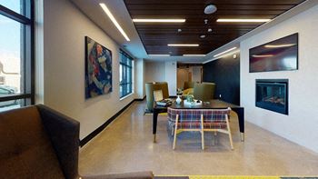 A modern living room with a brown couch, a wooden table, and a painting on the wall.