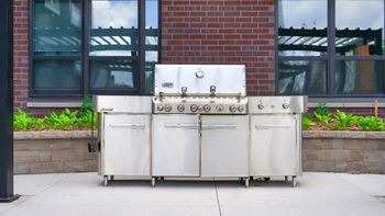 A large industrial-sized stainless steel oven with a door and a handle is on a concrete surface.