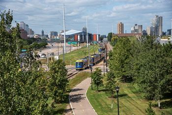 A train is passing by a park with a city skyline in the background.