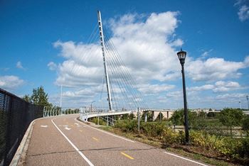 A pedestrian pathway with a lamp post and a bridge in the background.