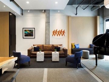 Minneapolis apartment for rent - A modern living room with a brown sofa, blue chairs, and a large abstract painting on the wall.