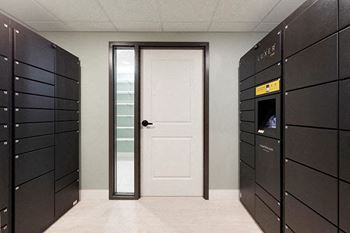 A hallway with a white door and a wall of lockers on the left.