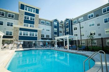 A swimming pool in front of a multi-story apartment building.
