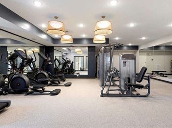A well-lit gym with a variety of equipment including treadmills, elliptical machines, and weight machines.