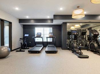A gym with treadmilers, exercise bikes, and a large ball.